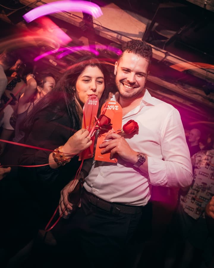Couple holding blanc. roses at a Valentine's party