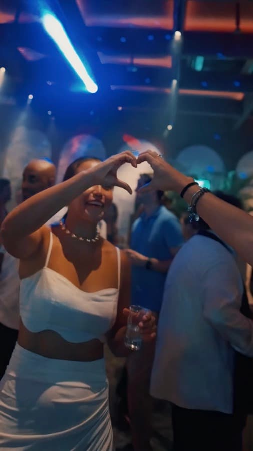 Guests making a heart shape with a drink in hand